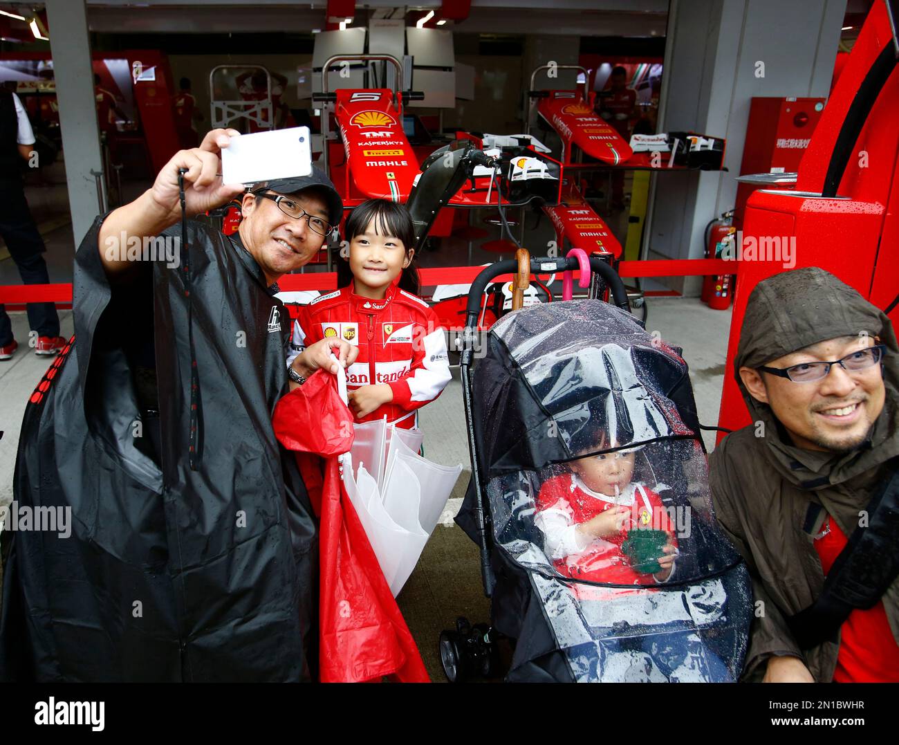 Fans take selfies outside the Ferrari garage at the Suzuka Circuit ahead of the Japanese Formula One Grand Prix in Suzuka, central Japan, Thursday, Sept. 24, 2015. (AP Photo/Shizuo Kambayashi) Stock Photo