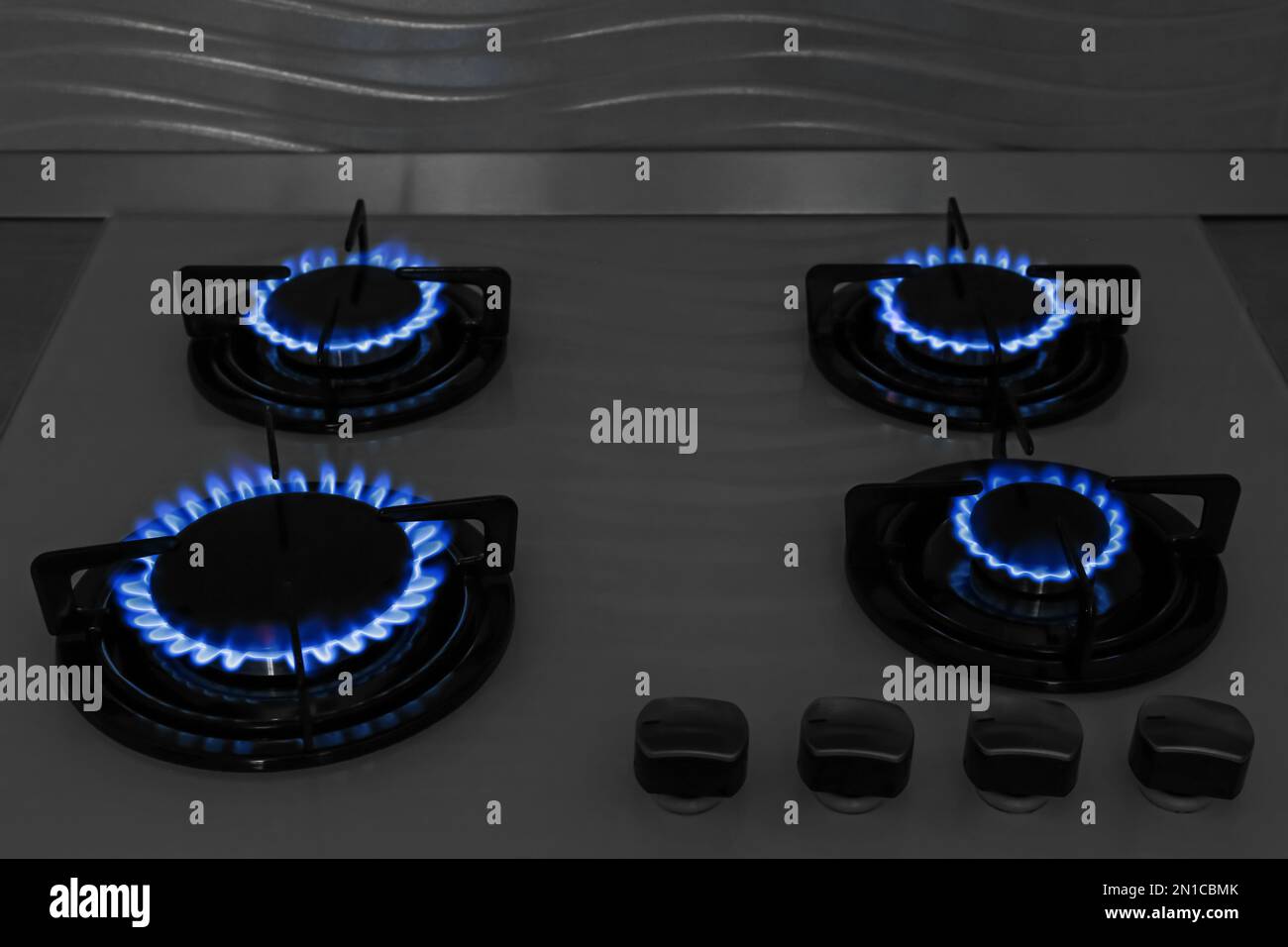 Modern gas cooktop with burning blue flames in kitchen at night Stock