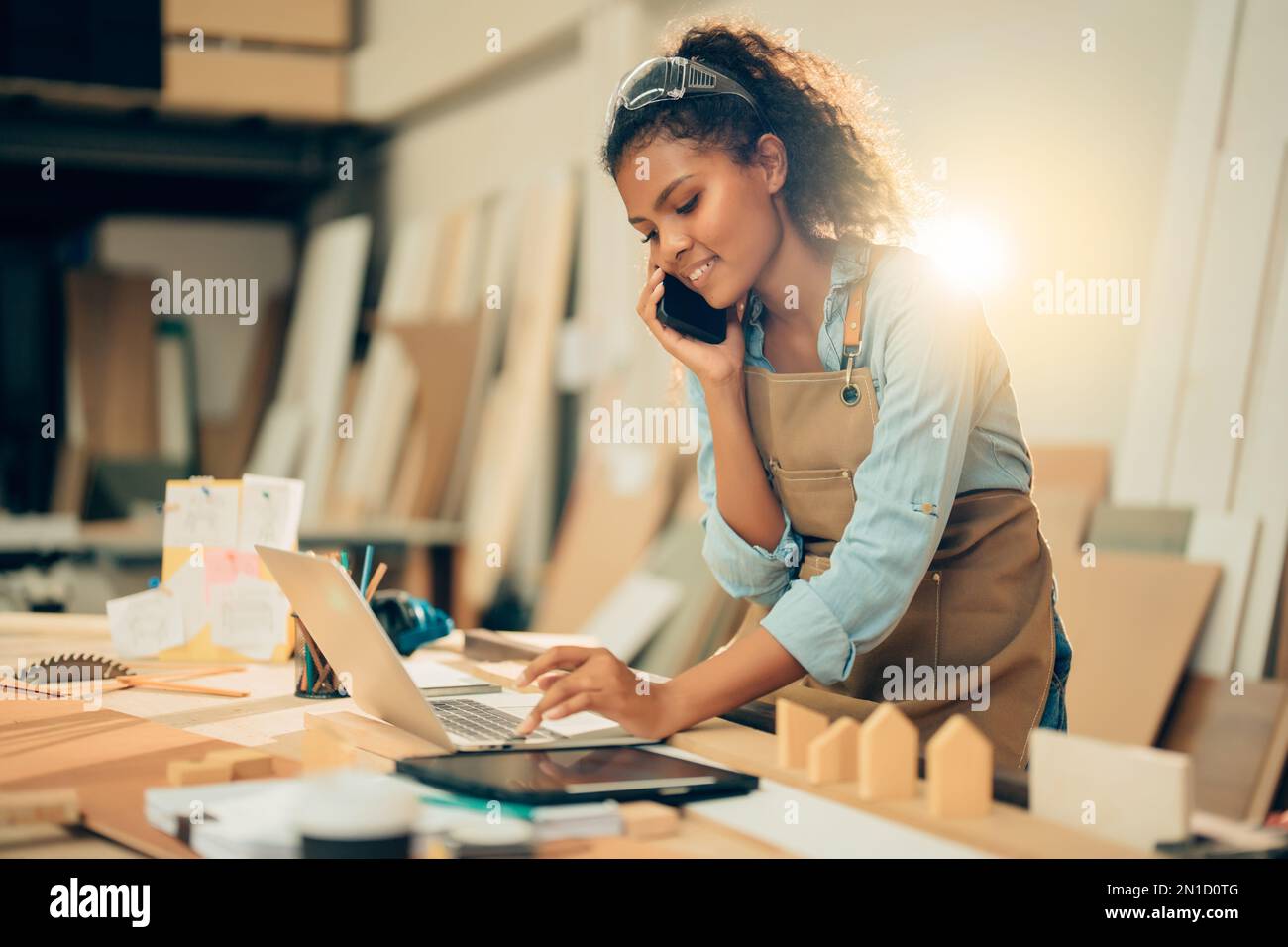 Smiling Young Asian female carpenter using laptop computer while ...