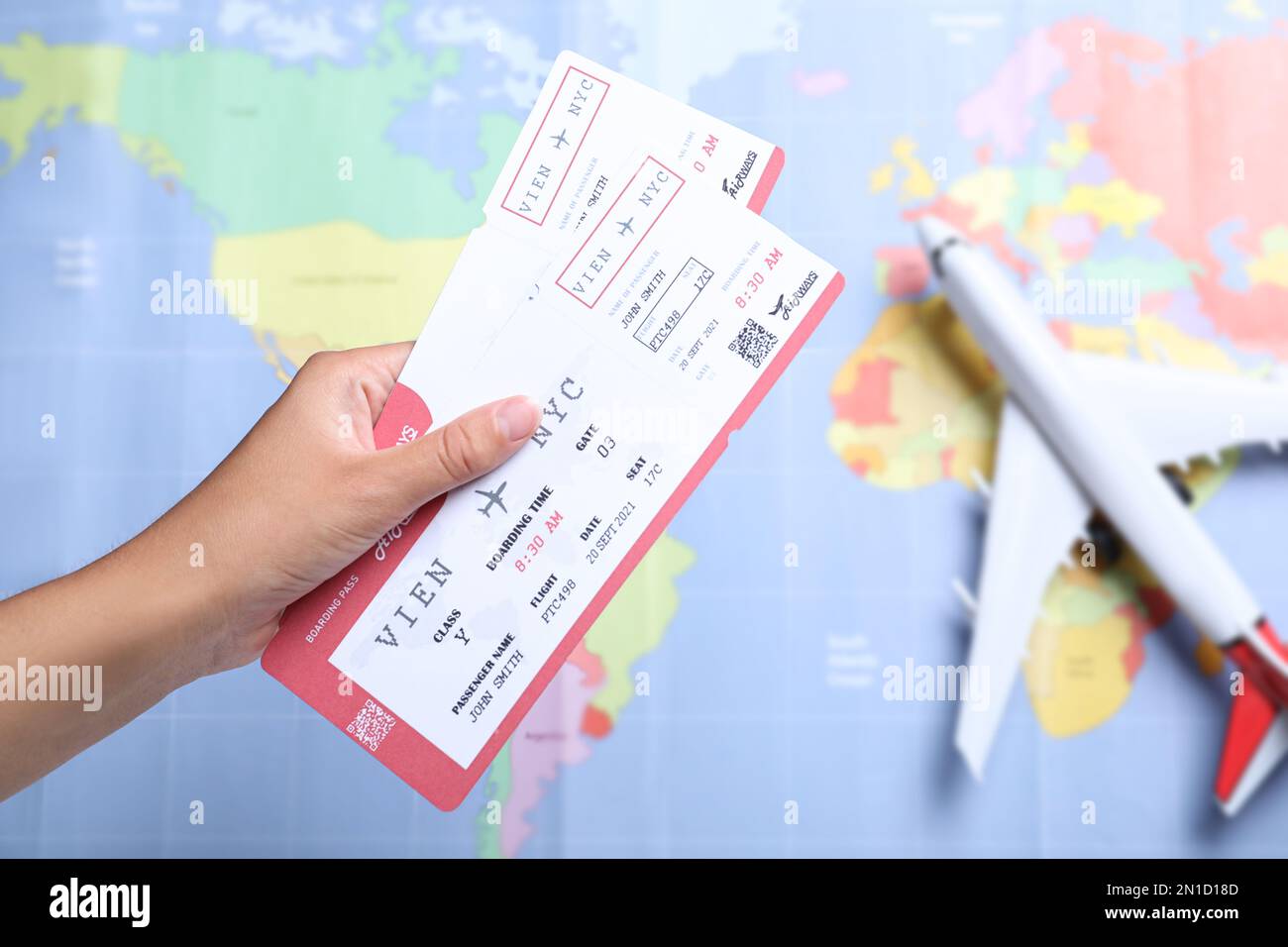 Woman holding airline tickets above world's map with toy plane, closeup
