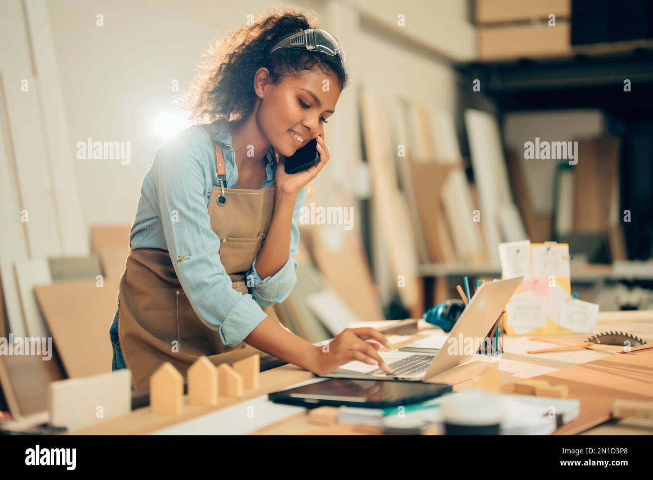 Smiling Young Asian female carpenter using laptop computer while ...