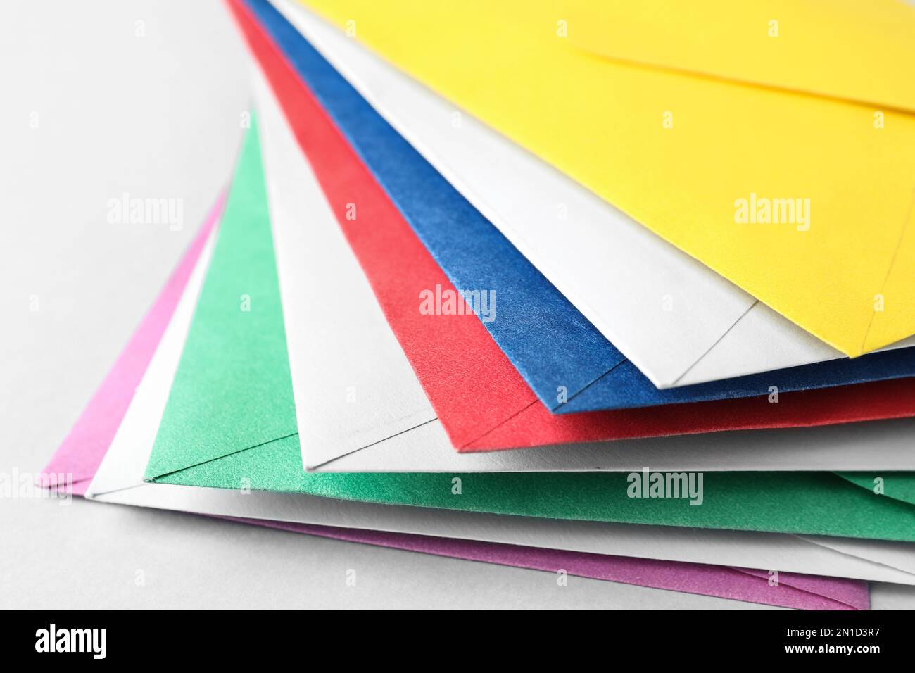 Stack of colorful paper envelopes on light background, closeup Stock Photo