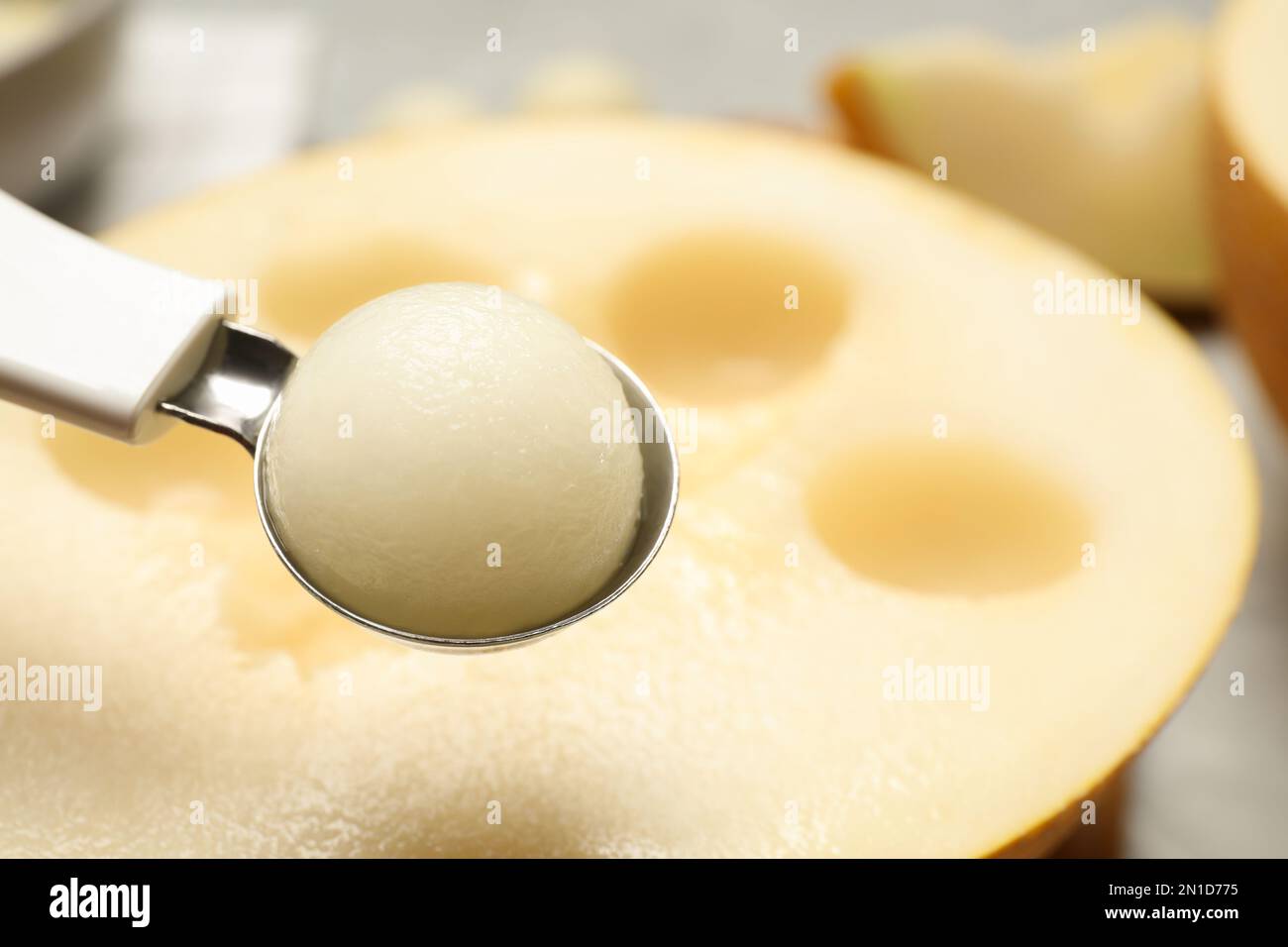 Scoop with melon ball on blurred background, closeup. Space for text Stock Photo