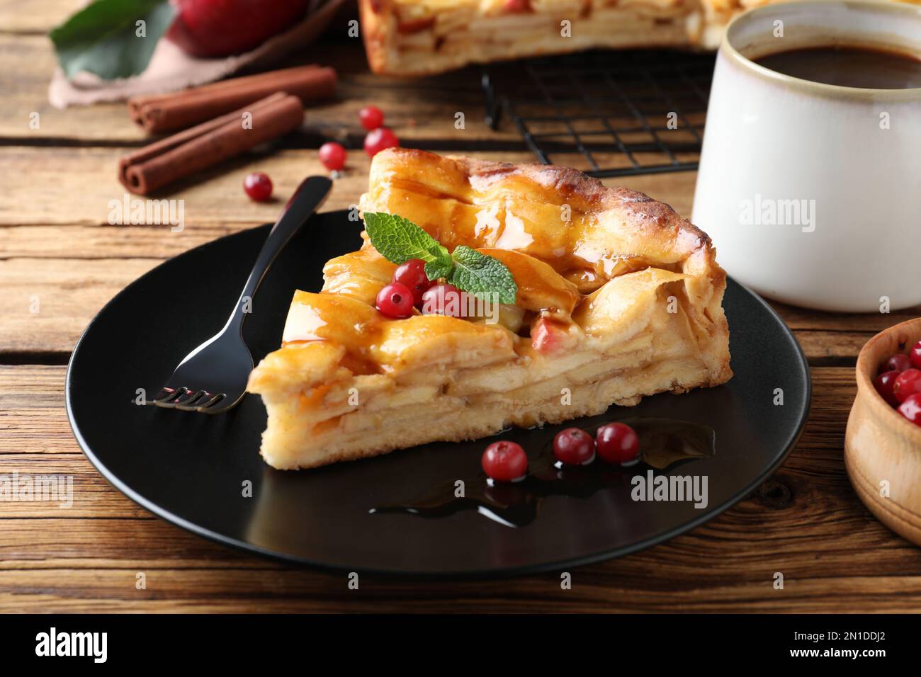 Slice of traditional apple pie with berries served on wooden table, closeup Stock Photo