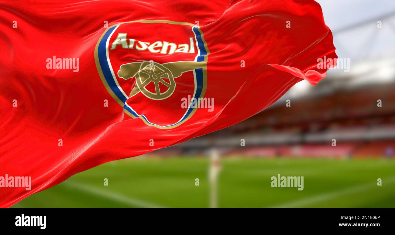 London, UK, DEC 2022: flag of Arsenal Football Club waving with the Emirates Stadium blurred in the background. Rippled Fabric. Textured background. S Stock Photo