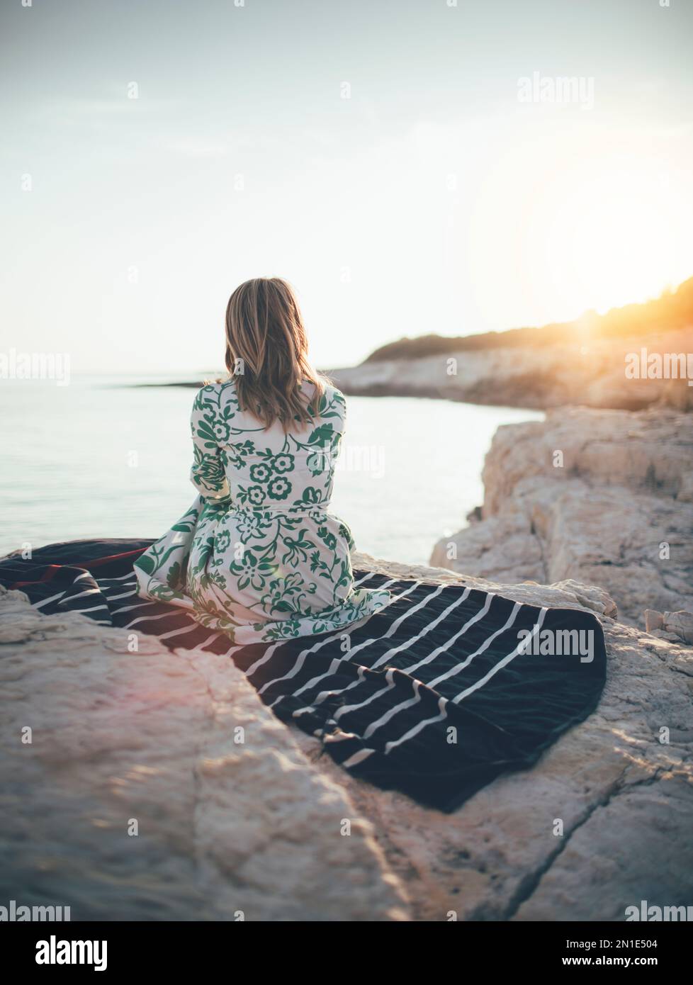 Lonely young woman sitting on beach Stock Photo