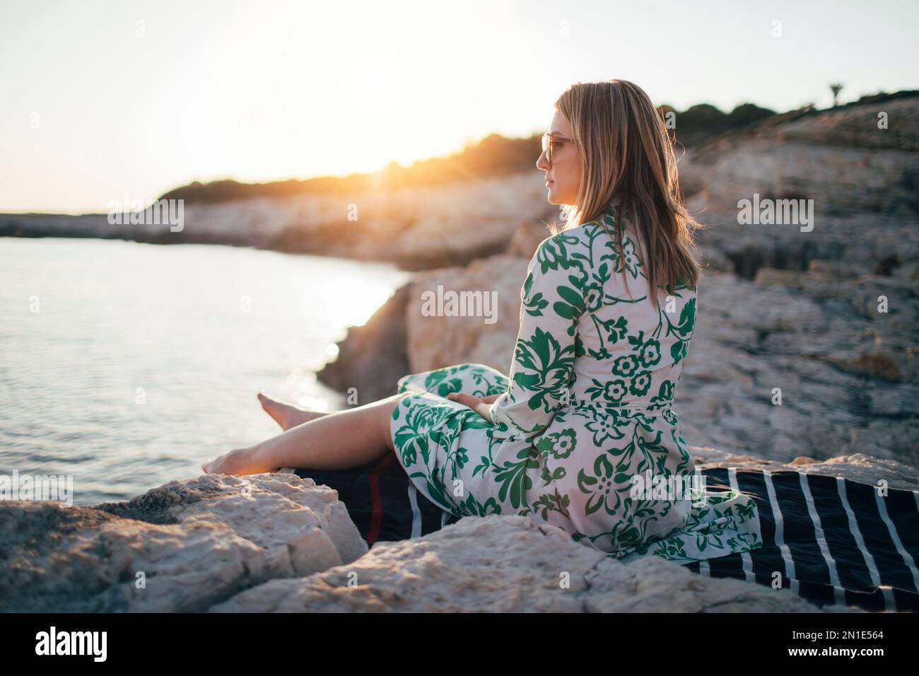 Lonely young woman sitting on beach Stock Photo