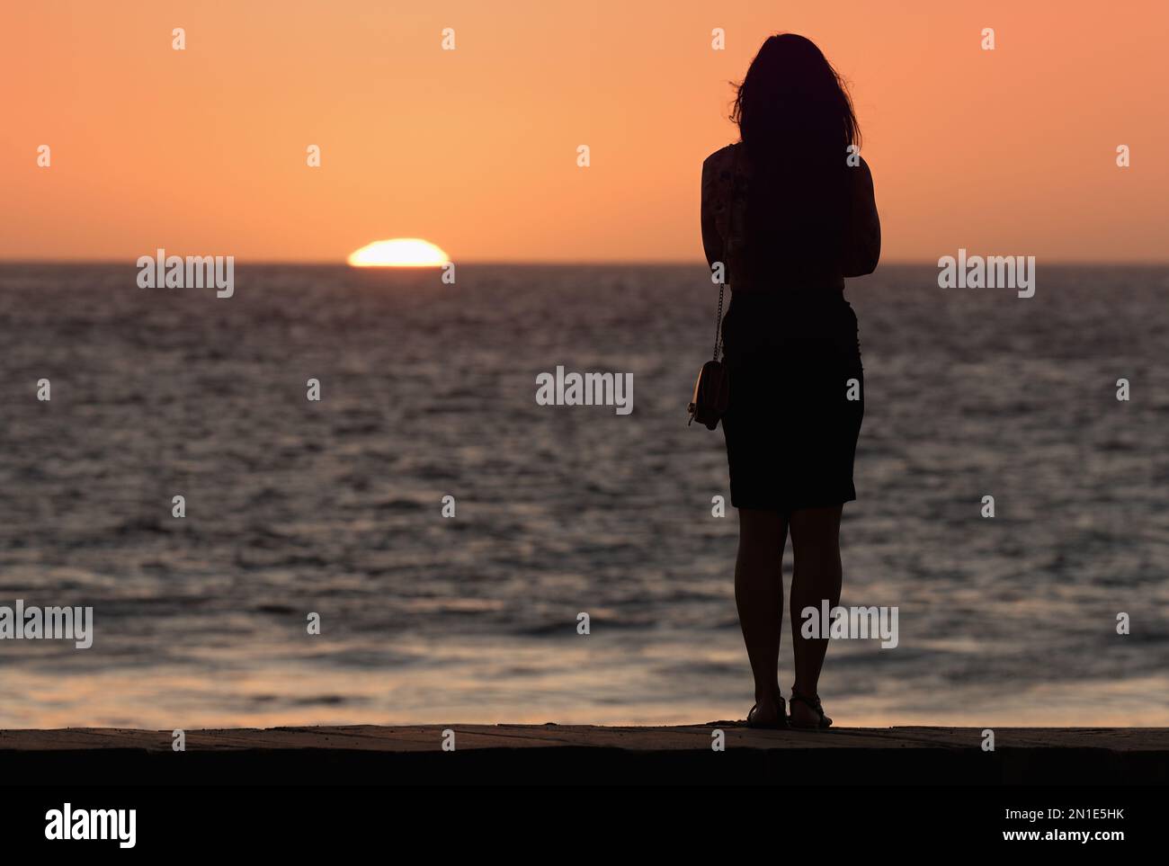 Silhouette of sensual woman watching sunset at the beach Stock Photo ...