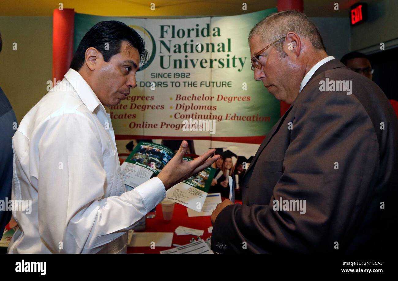 FILE - In this July 15, 2015 file photo, Luigi Valdivieso, left, talks  about job opportunities to Richard Solano at a job fair in Miami Lakes,  Fla. The U.S. Labor Department reports