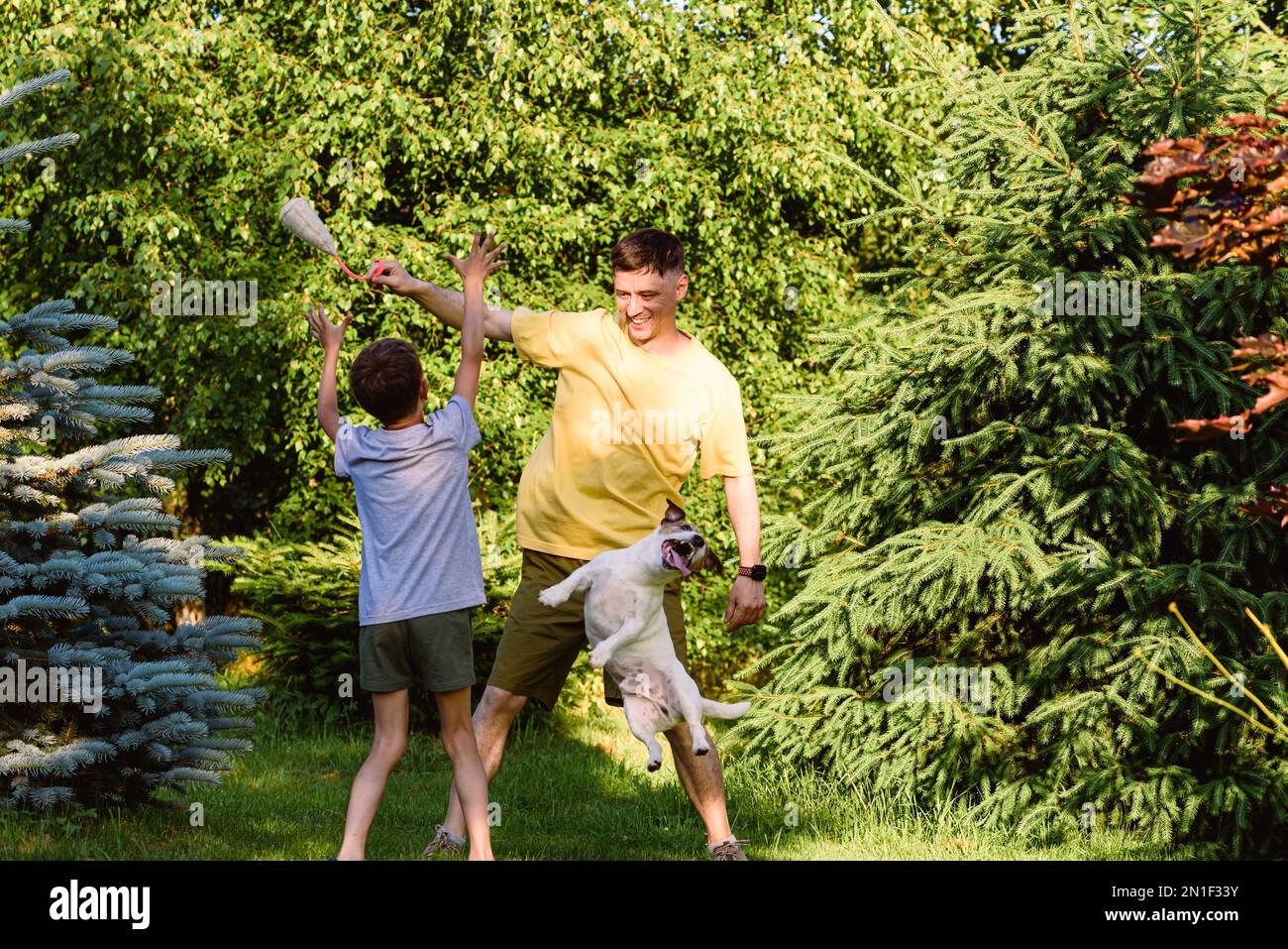 Laughing father and son playing outside with family pet dog Stock Photo