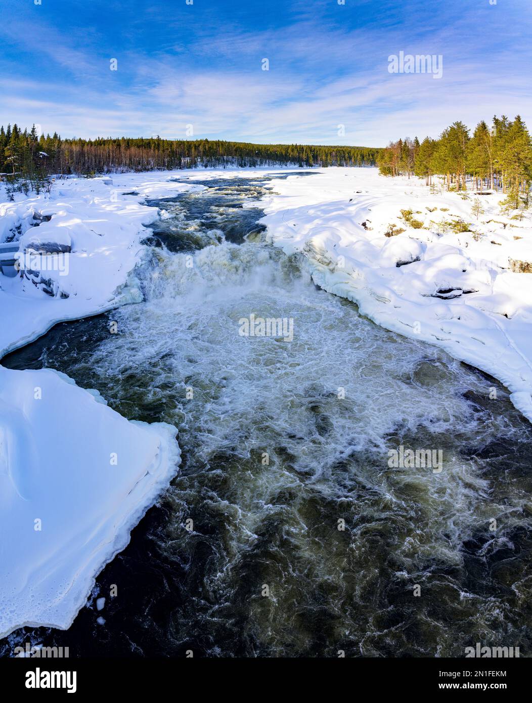 Cold rapids of waterfall running fast through the snowy Arctic forest