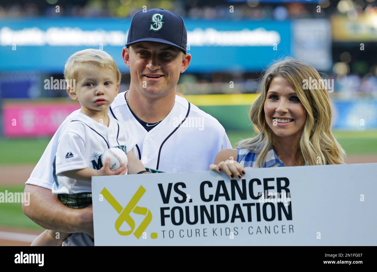 Seattle Mariners third baseman Kyle Seager holds his son Crue, 1 1/2, as he  stands with his wife Julie during a charity presentation before a baseball  game against the Colorado Rockies, Saturday