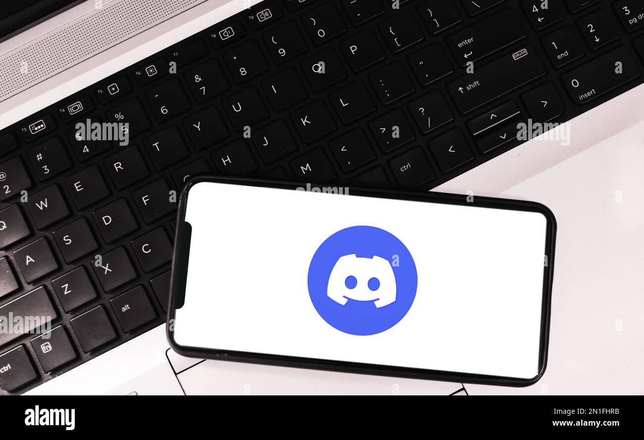 Discord application on mobile screen with laptop in the backdrop stock