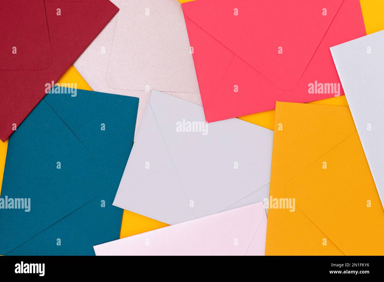 Multicolored envelopes scattered on a yellow background. Creative background. Stock Photo