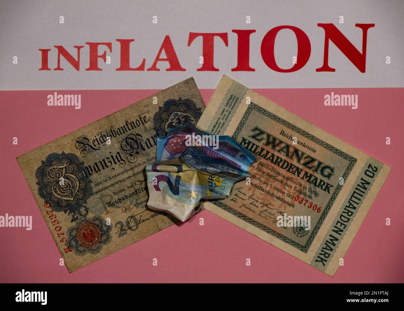 Crumpled 20 Euro banknote on top of old German Mark banknotes with pink background, lettering of the word 'INFLATION' in large characters at the top Stock Photo