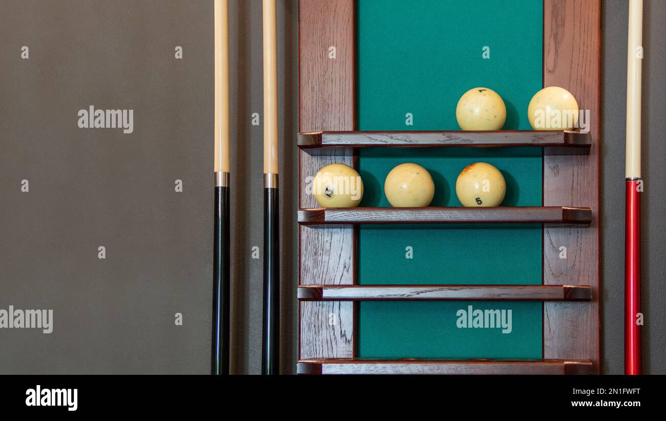 Rack with equipment for sporty game - billiard balls and cues. Horizontal banner with copy space. Stock Photo