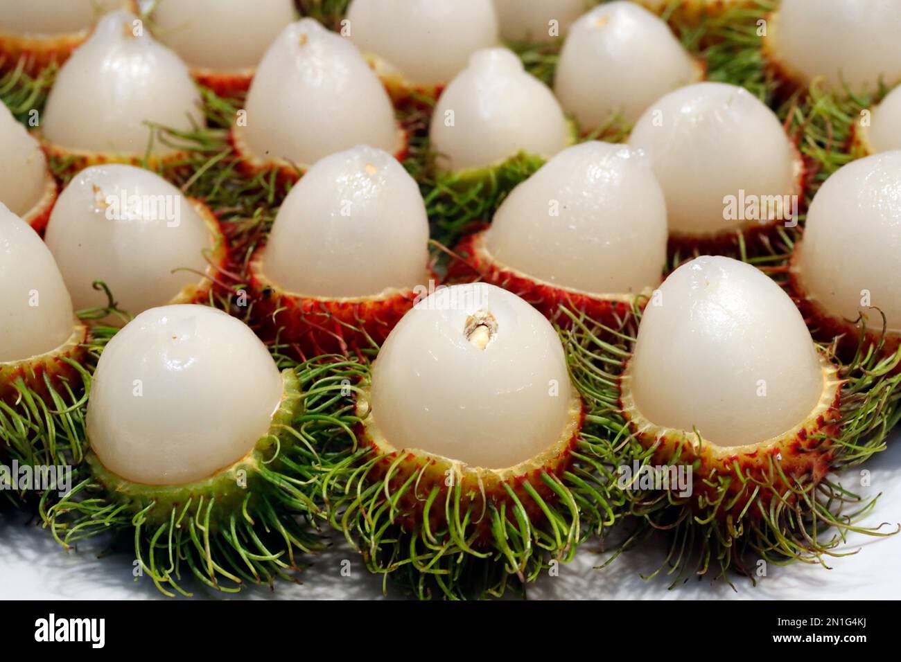 Cut red rambutan on a plate, exotic fruit, Vietnam, Indochina, Southeast Asia, Asia Stock Photo
