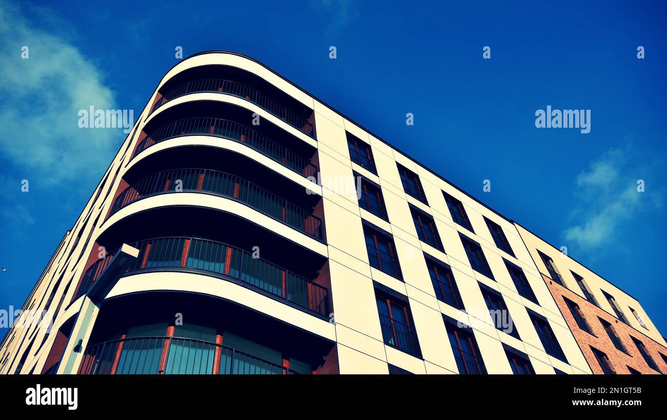 View of architectural exterior detail of residential apartment building with brick facade. Modern brick apartment building with red facade. Retro styl Stock Photo