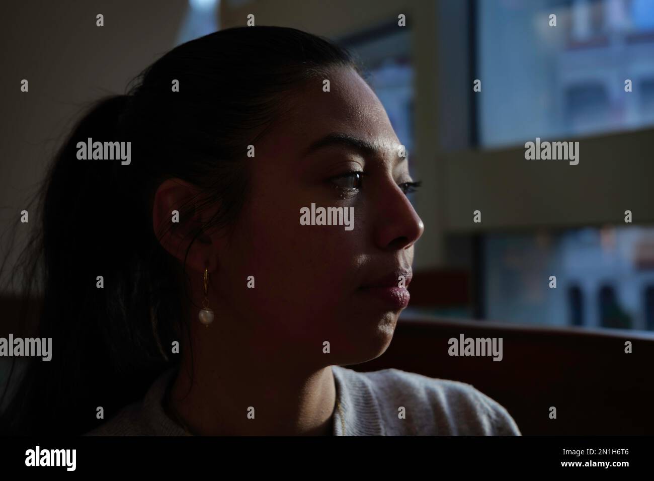 London - 03 06 2022: Close up of a girl looking out the window with Latin or South American features Stock Photo