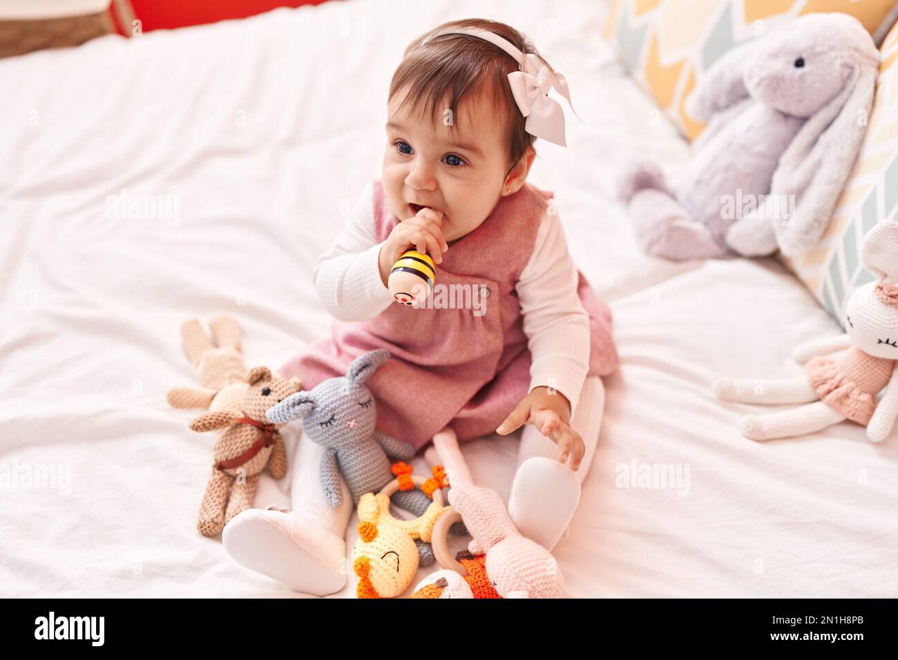 Adorable hispanic baby bitting maraca sitting on bed at bedroom Stock ...