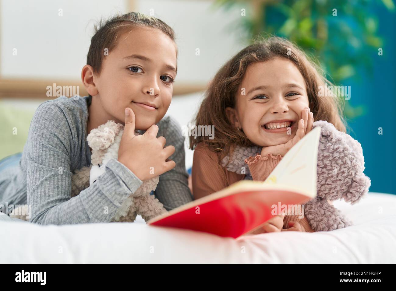 Two Kids Reading Story Book Lying On Bed At Bedroom Stock Photo - Alamy