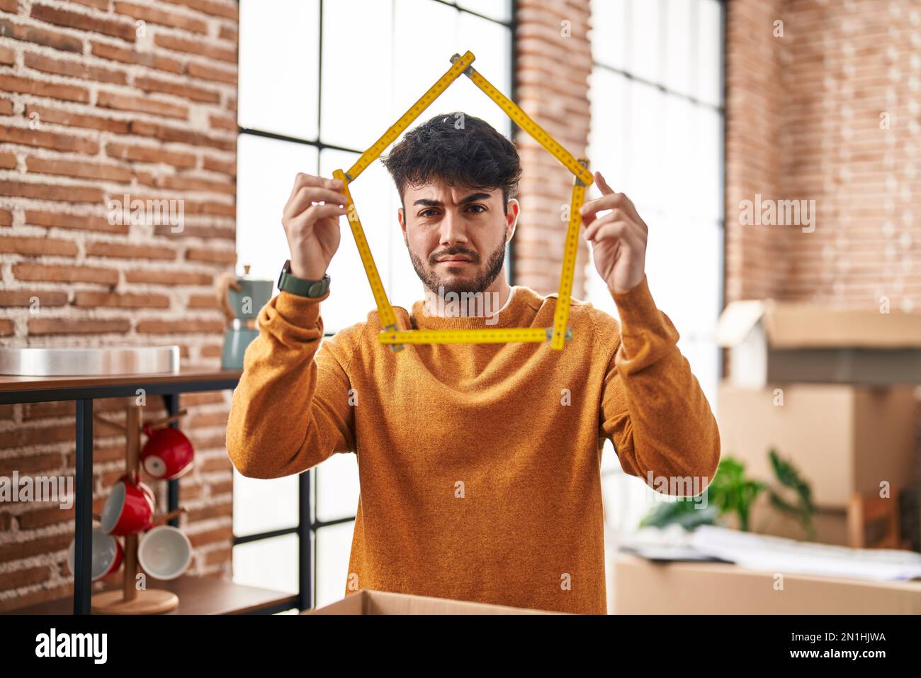 Hispanic man with beard moving to a new home holding ruler clueless and ...
