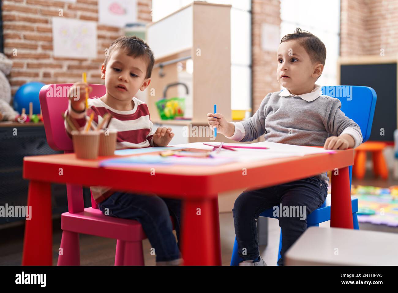 Two kids preschool students sitting on table drawing on paper at ...