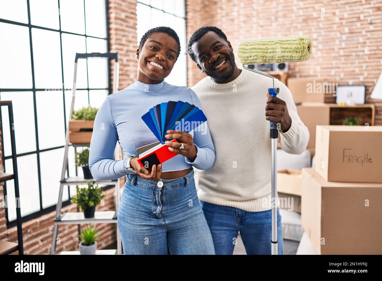 Young african american couple moving to a new home choosing walls color ...