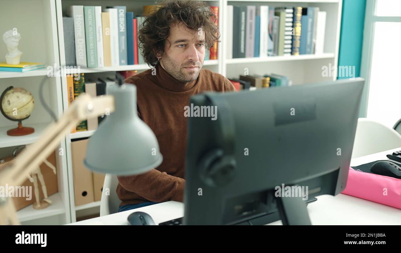 Young hispanic man student using computer studying at library ...