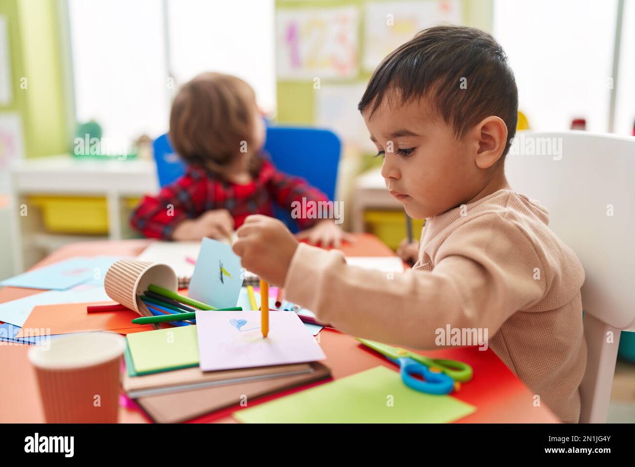 Two kids preschool students sitting on table drawing on paper at ...
