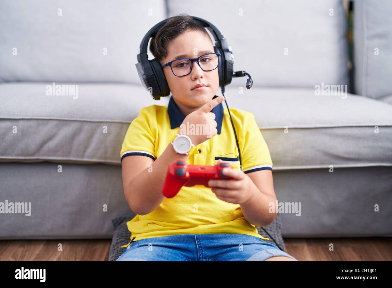 Kid Using Controller Young hispanic kid playing video game holding controller wearing ...