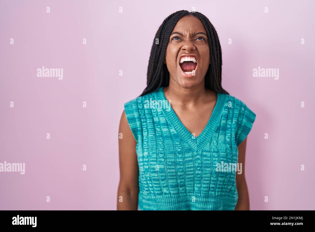 Young african american with braids standing over pink background angry ...