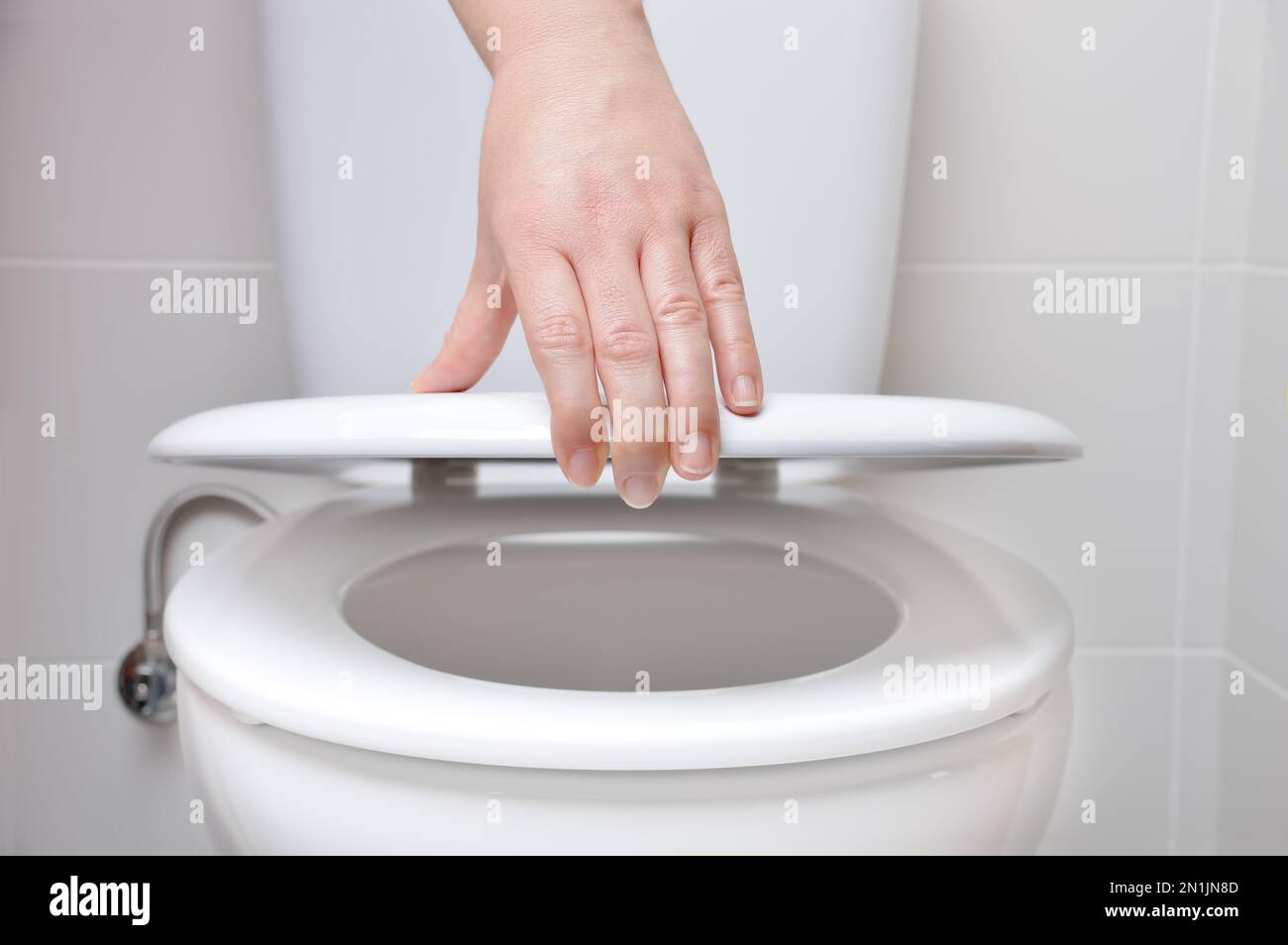 hand of a woman closing the lid of a toilet Stock Photo