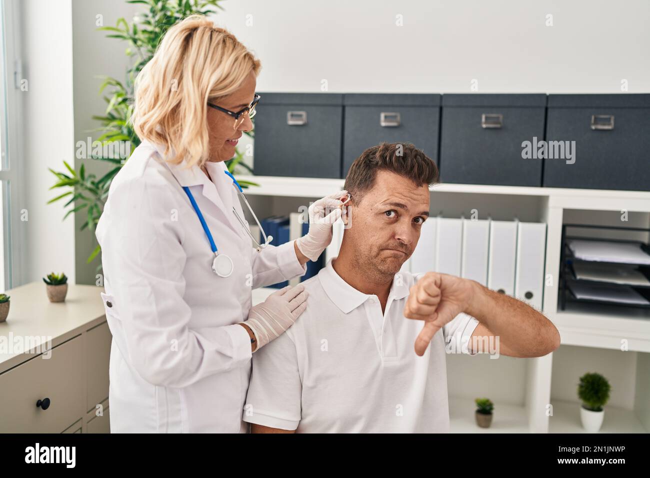 Hispanic man getting medical hearing aid at the doctor with angry face ...