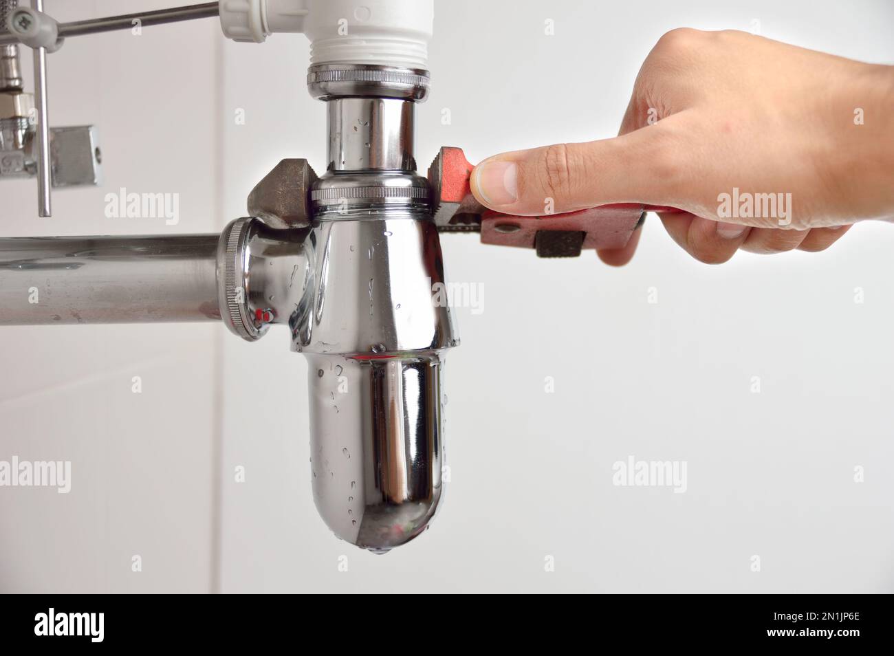 plumber fixing sink pipe with adjustable wrench Stock Photo