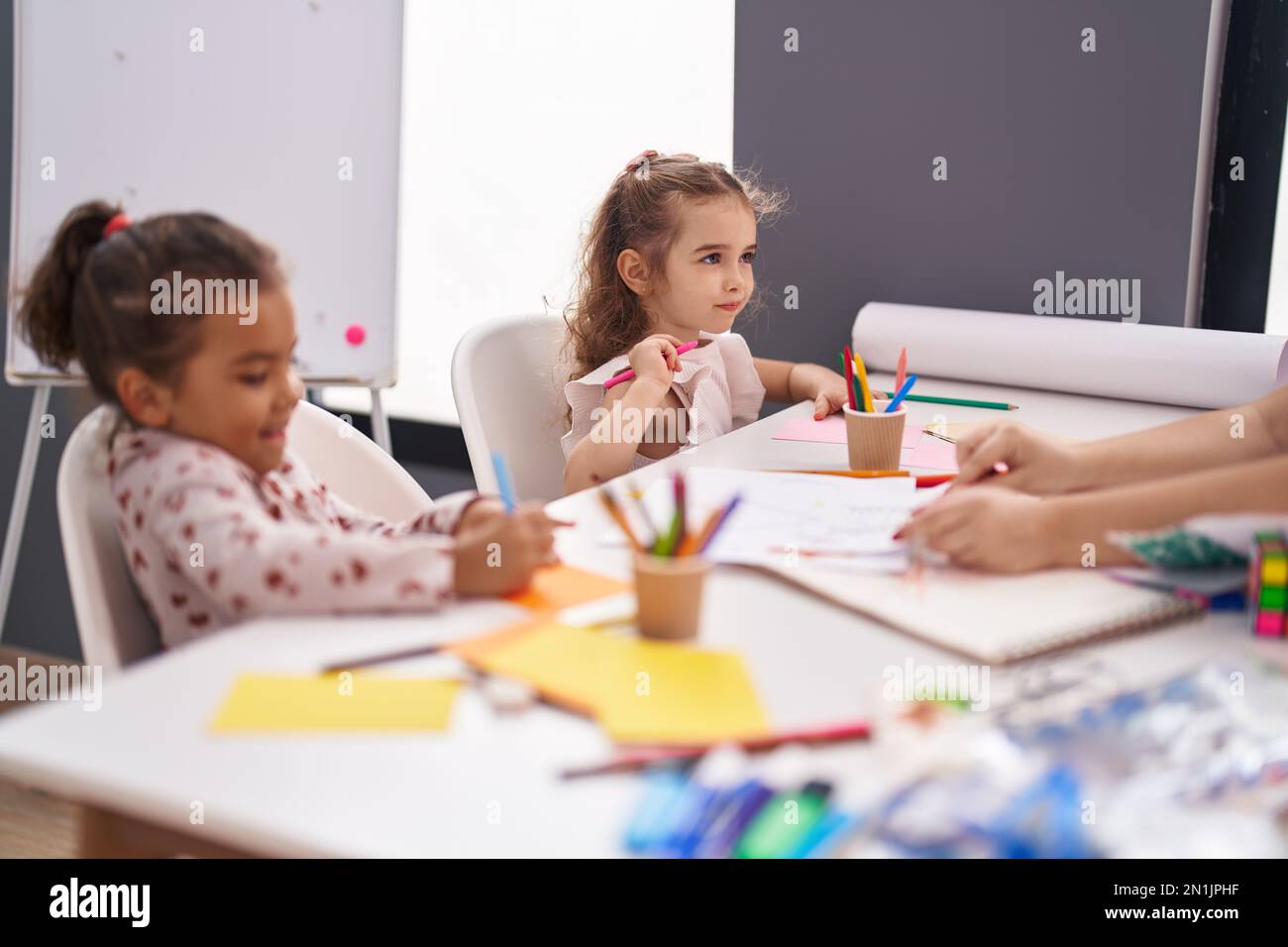 Two kids preschool students sitting on table drawing on paper at ...