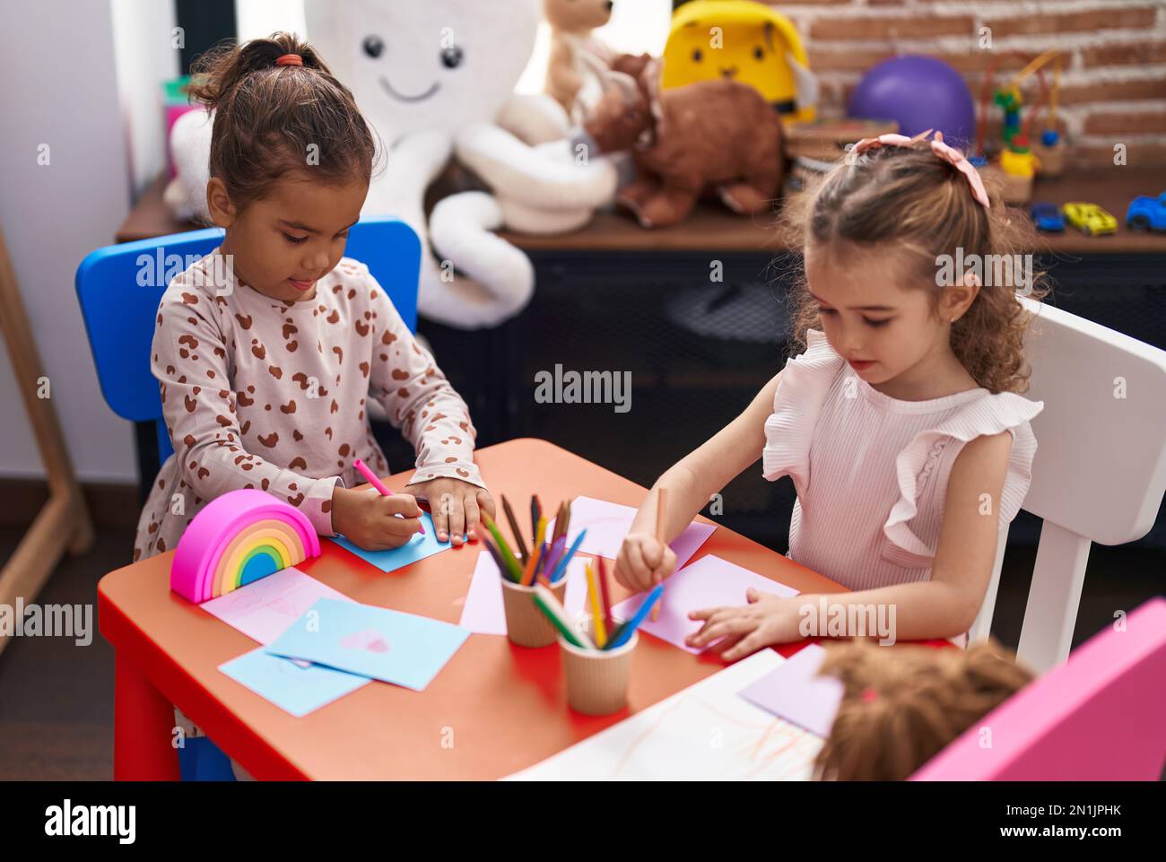 Two kids preschool students sitting on table drawing on paper at ...