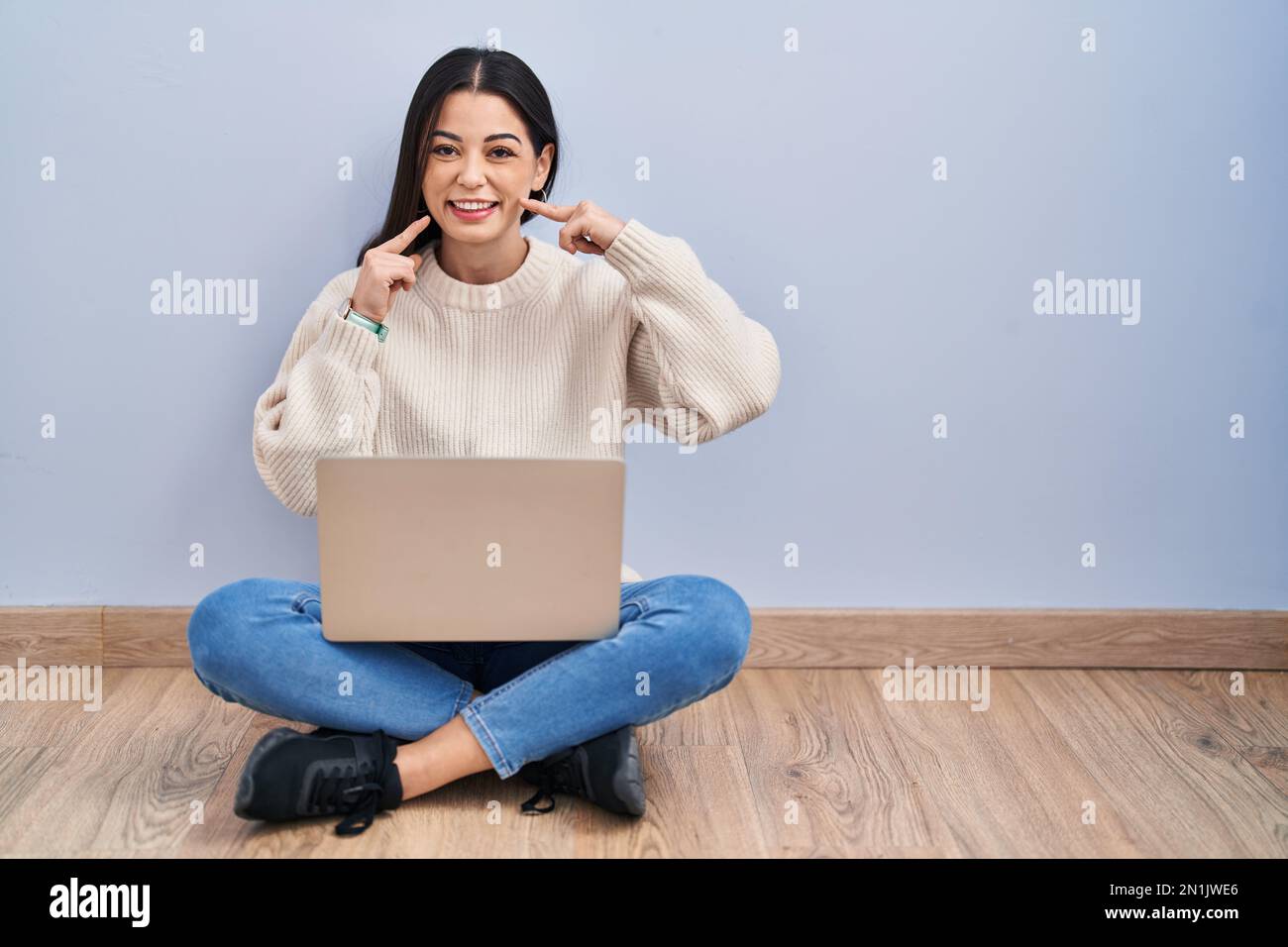 Young woman using laptop sitting on the floor at home smiling cheerful ...