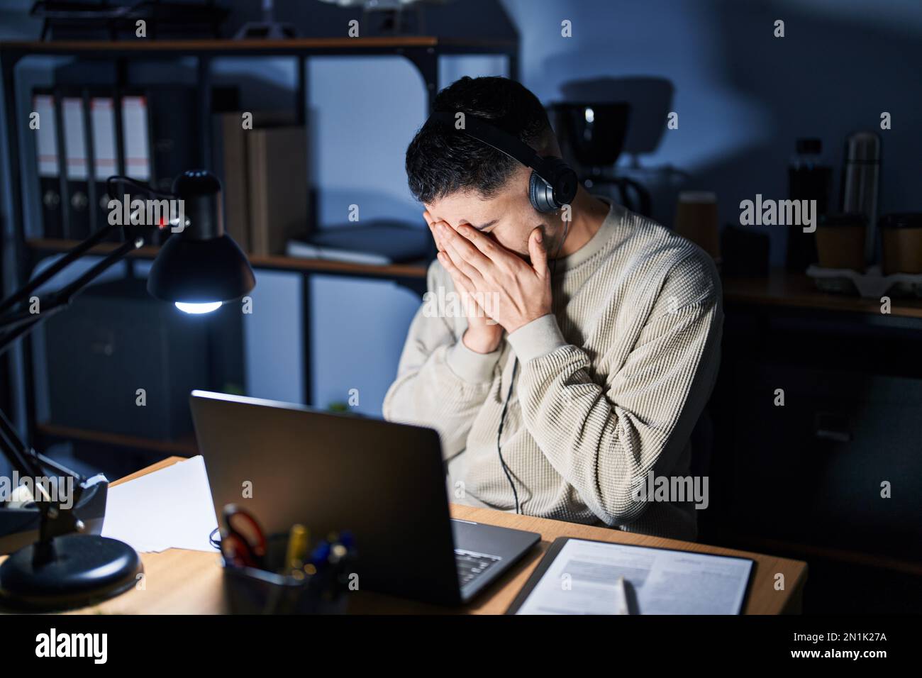 Young handsome man working using computer laptop at night with sad ...