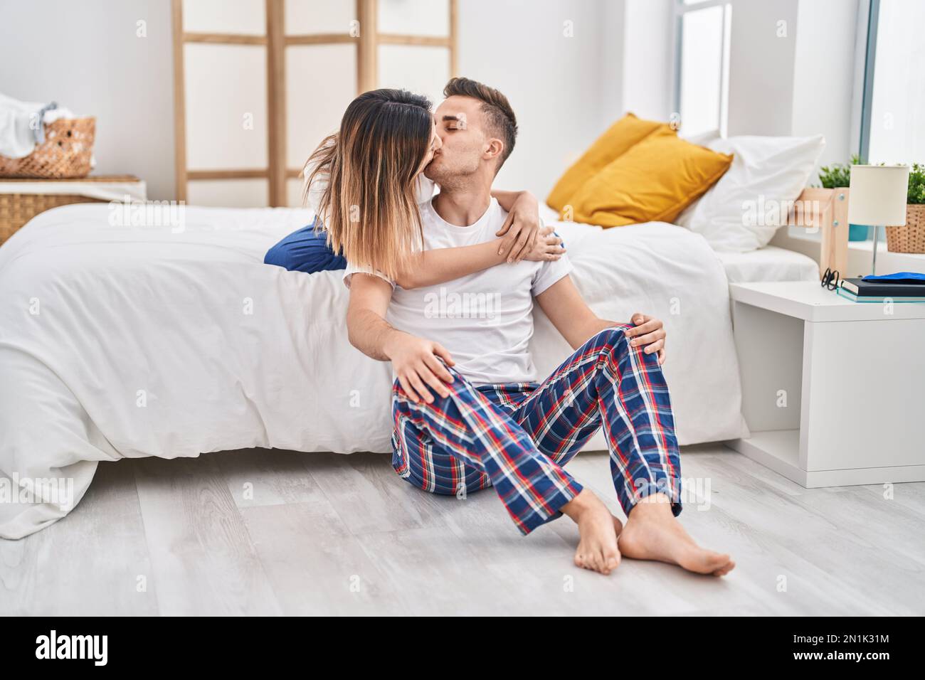 Man and woman couple sitting on bed hugging each other and kissing at