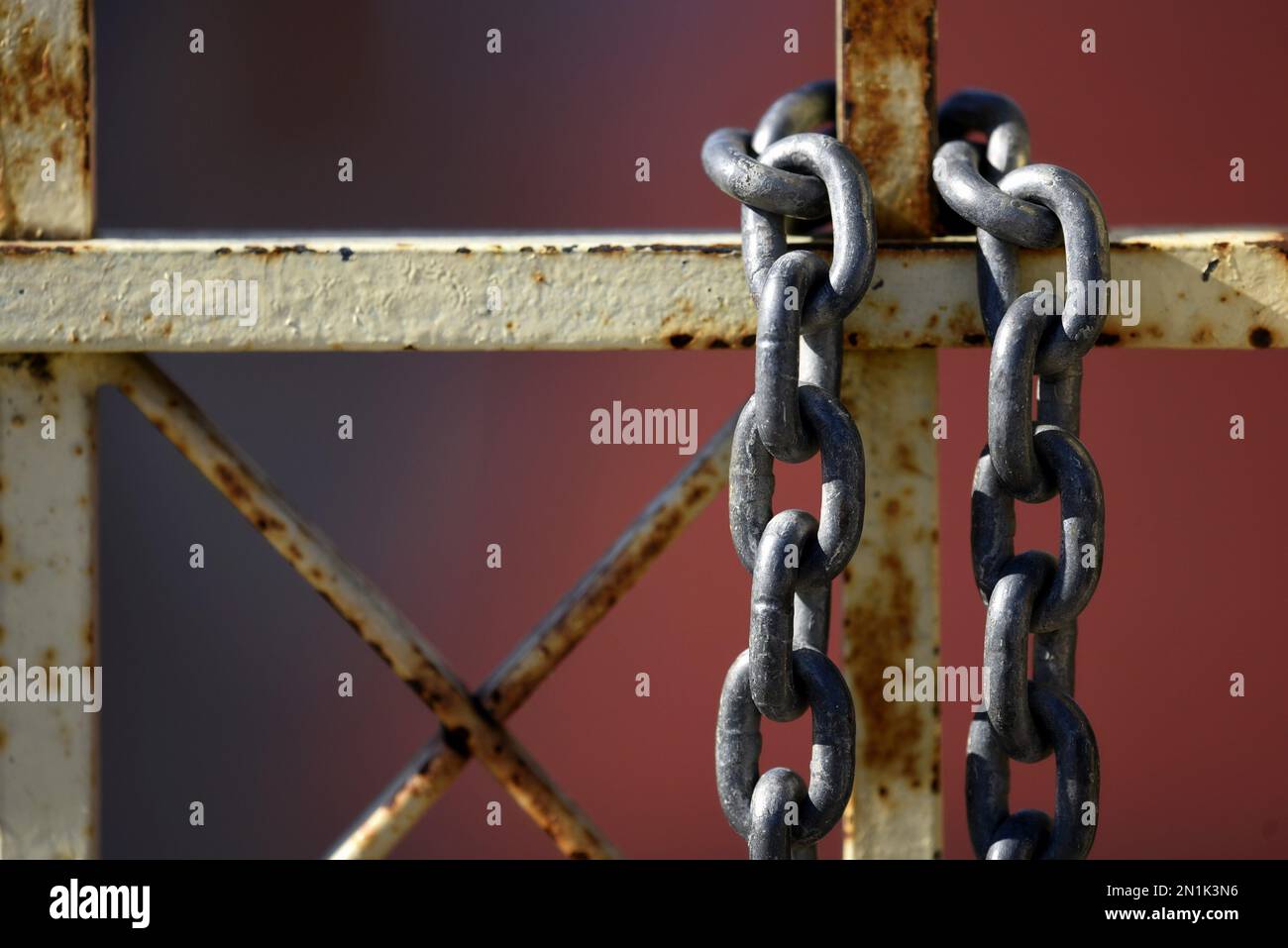 Heavy duty chain over a rusty wrought iron entrance gate railing Stock