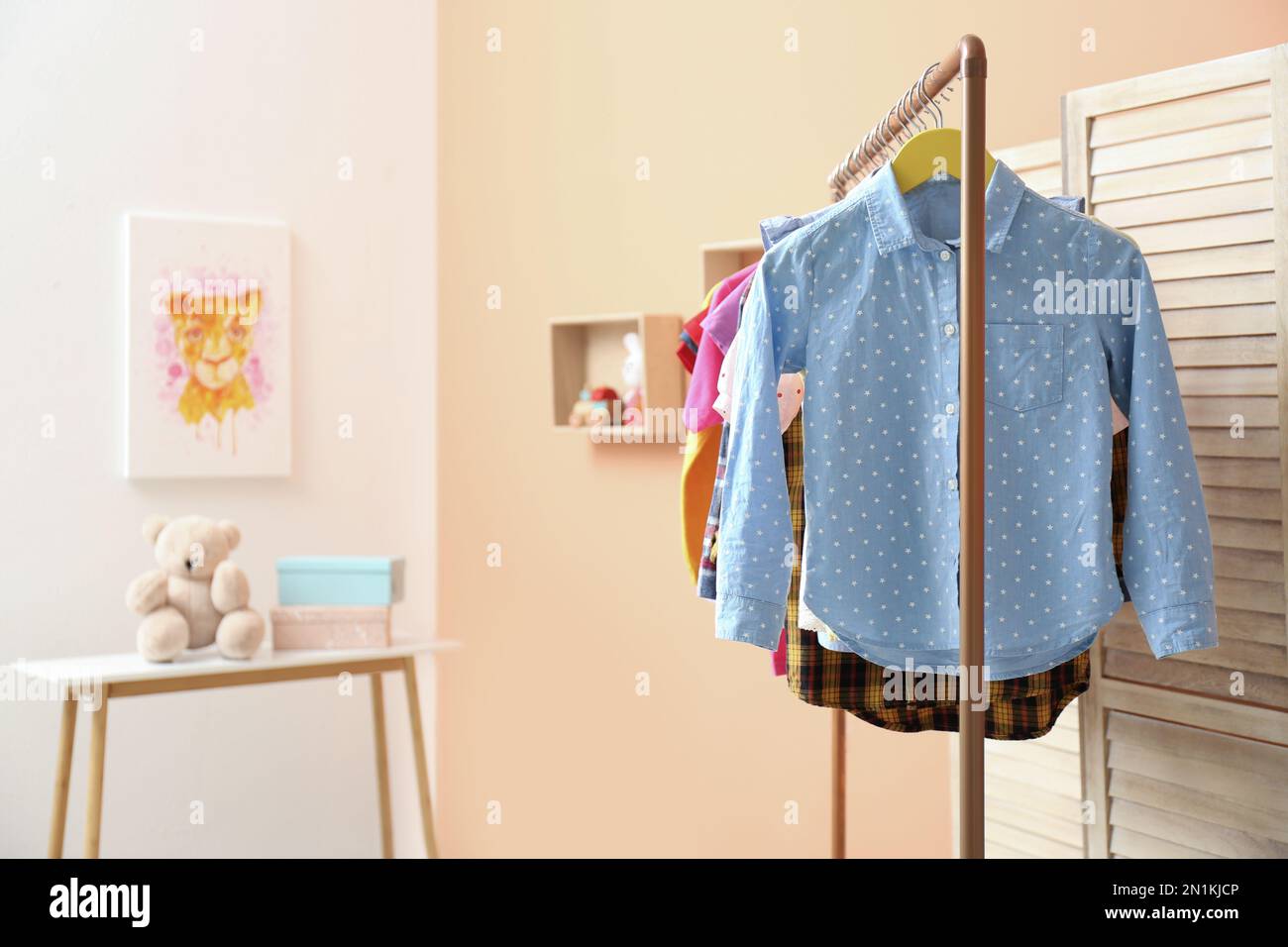 Cute little girl choosing festive dress hanged in pink cupboard comfortable  clothes vertical storage Stock Photo - Alamy
