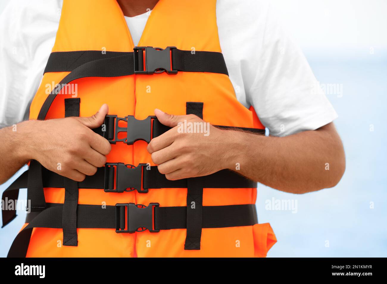 Male lifeguard putting on life vest near sea, closeup Stock Photo Alamy