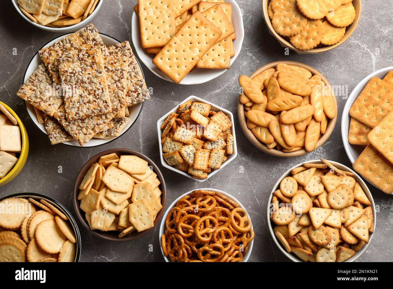Different delicious crackers in bowls on grey table, flat lay Stock Photo