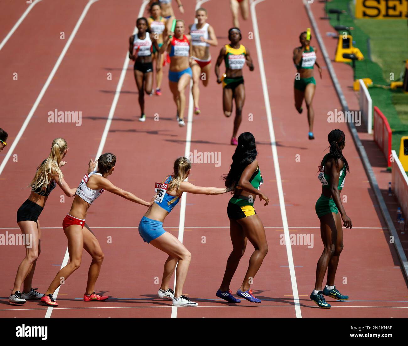 Competitors in a women's 4x400m relay round one heat reach for a baton