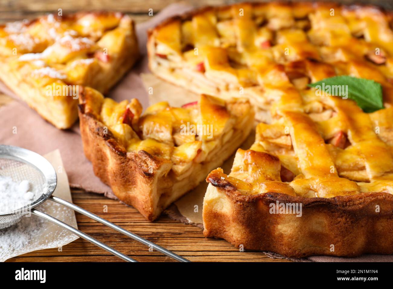 Traditional apple pie and sugar powder on wooden table, closeup Stock Photo