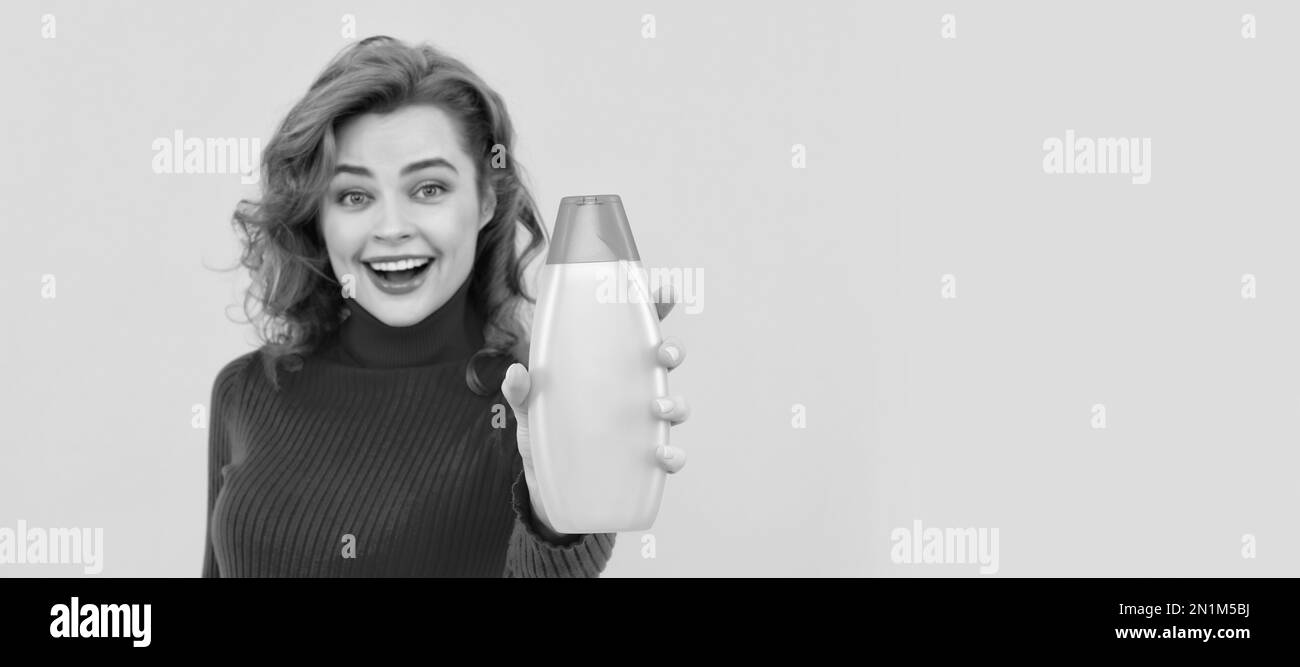 happy redhead woman curly dyed hair presenting body care product of