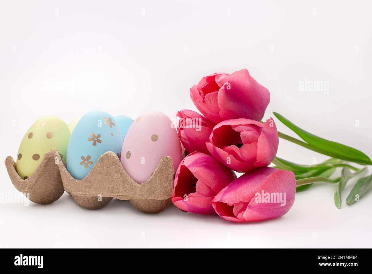 Pink tulips with colored eggs on white background. Easter. Copy space Stock Photo