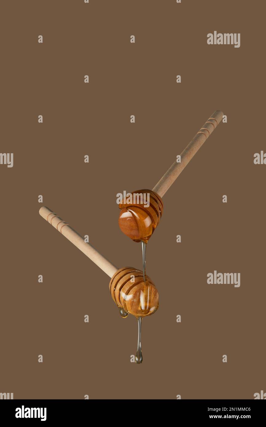 Honey dippers dripping with sweet sticky honey photographed against a plain background with