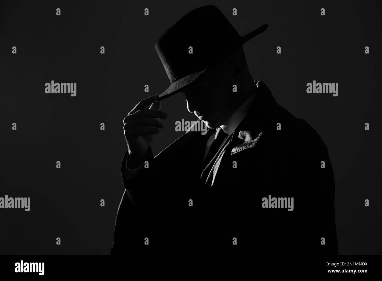 Old fashioned detective in hat on dark background, black and white ...